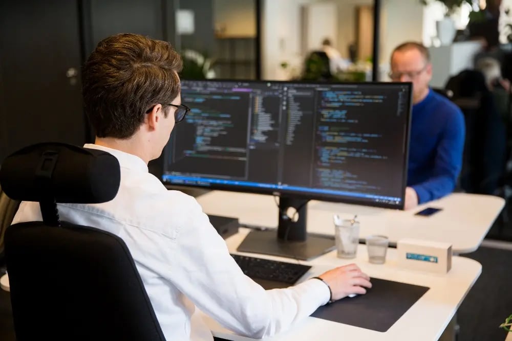 An image of a person looking at a computer screen displaying code. 